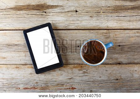 Tablet computer and a cup of black coffee on a wooden table. View from above bisness