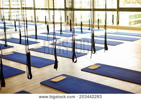 Many aerial yoga exercise equipment with blue cushions in gym for aerial silk (yoga fly) for background or texture - new trend of exercise concept.