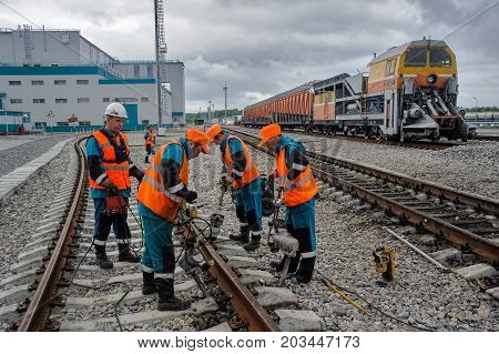 Tobolsk, Russia - July 15. 2016: Sibur company. Denisovka railway station. Railway workers repairing rail in rainy weather