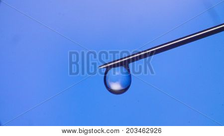 Macro shooting of water drop falling from the syringe needle