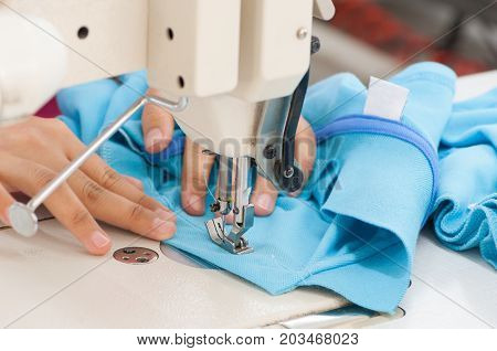 closeup seamstress on the machine sews clothes at a garment factory