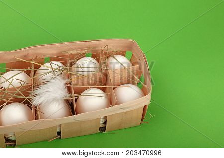 White Chicken Eggs In Wooden Container Over Green