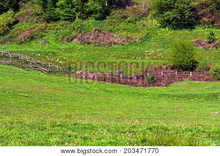 Panorama of a typical alpine meadow with wood fence. Mountain and valley