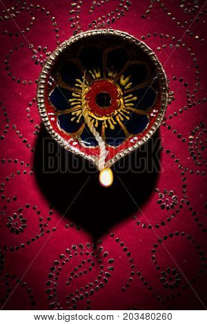 stock photo of beautiful diwali diya, isolated over decorative background, moody lighting and selective focus