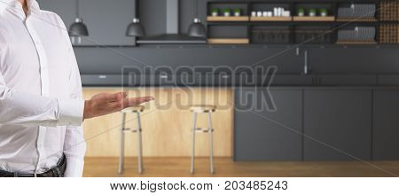 Man's hand presenting showing blurry kitchen interior with counters and equipment. Sell concept. 3D Rendering