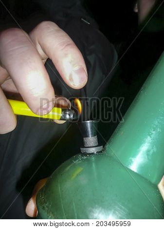 Ignition Of Cigarette Lighter In A Bong. Bong Smoking. Smoking Through The Bong Is Marijuana.