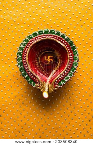 stock photo of beautiful diwali diya, isolated over decorative background, moody lighting and selective focus