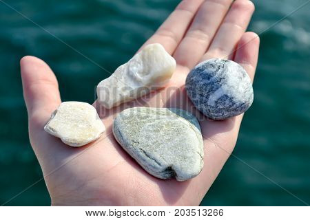 Girl Hand Full With Small Stones On The Beach