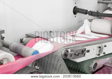 factory and equipment for the production of female sanitary napkins. women hygiene pads on a conveyor belt closeup