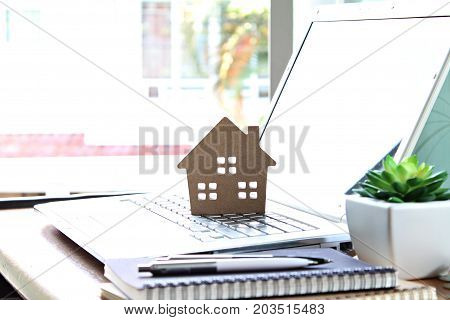 Business, finance, savings, property ladder or mortgage loan concept : Wood house model on computer laptop