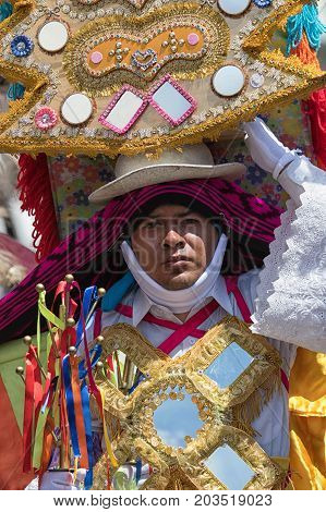 June 17 2017 Pujili Ecuador: indigenous kichwa man balancing a large headdress during Corpus Christi parade while dancing on the street