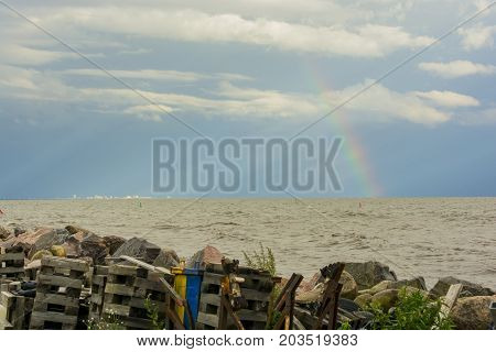 garbage on the shore of the reservoir river sea ocean on the horizon in the sunlight city and rainbow