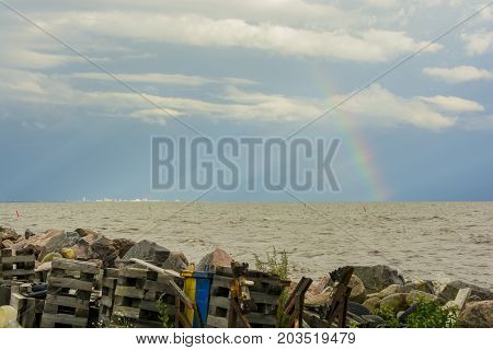 garbage on the shore of the reservoir river sea ocean on the horizon in the sunlight city and rainbow