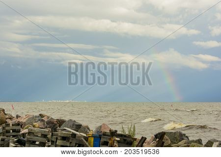 garbage on the shore of the reservoir river sea ocean on the horizon in the sunlight city and rainbow