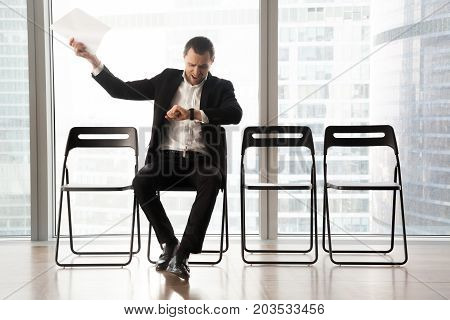 Distraught impatient businessman looking at wristwatch and yelling in anger because of tedious wait. Hand with resume document thrown in the air. Unhappy job candidate or businessman waiting too long.