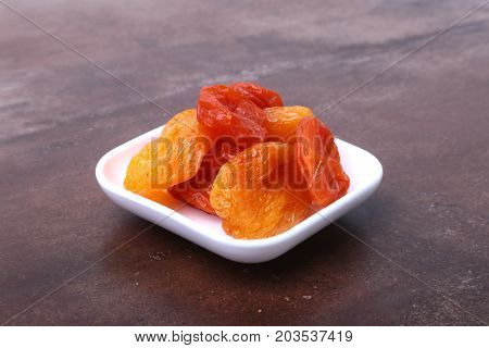 Delicious dried organic apricots in bowl isolated on stone table