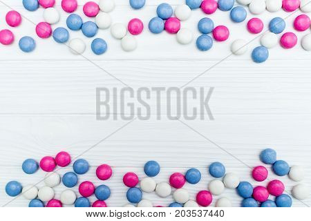 Frame from colorful mint coated candies texture on white wooden background. Top view. Copy space