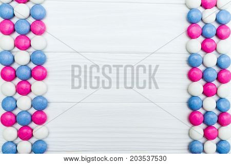 Frame from colorful mint coated candies texture on white wooden background. Top view. Copy space