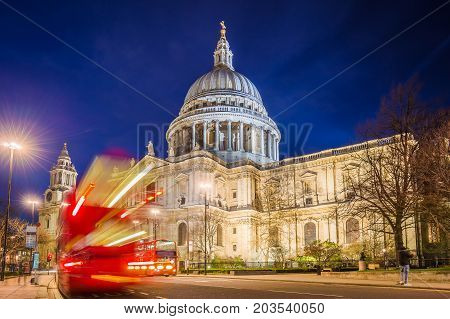 London England - The Saint Paul's Cathedral with famous old red double decker buses on the move at night