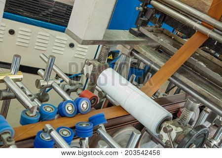 the machine glues the pvc tape onto the aluminum profile. workshop for the production of PVC profile