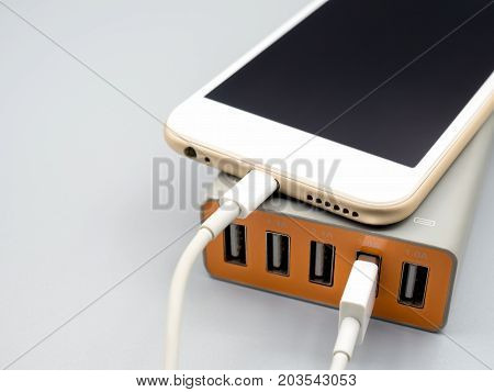 Close-up image of smart phone charging with multiport USB power adaptor on gray background with copy space Selective focus