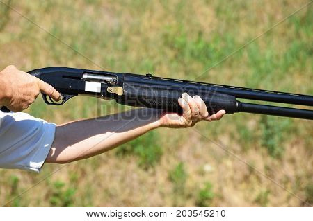 Man holds a shotgun outdoor in summer