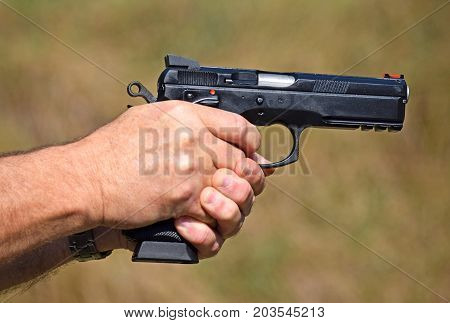Shooting with a pistol outdoor in summer