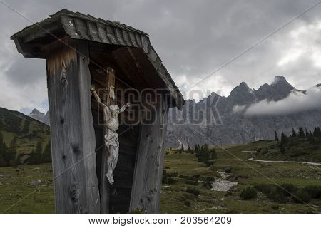 cross in the karwendel alps with clouds in fall