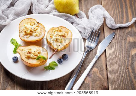 Pears baked with Ricotta cheese nuts honey and cinnamon on rustic wooden background