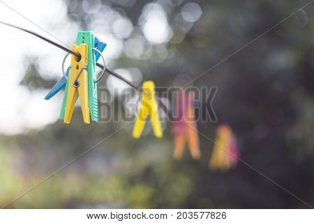 colored clothespins hanging on a rope with blurred background