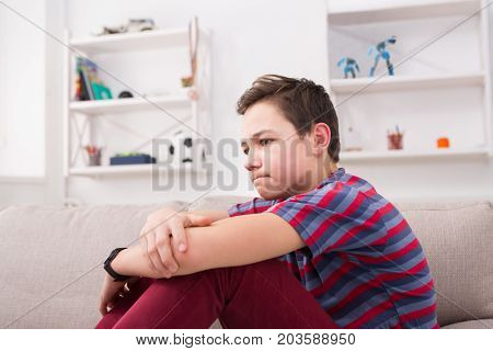 Unhappy lonely teenage boy at home, thinking about something, pubertal period, psychological problem. Lost in thoughts.