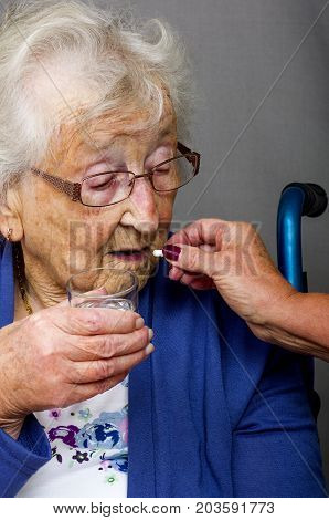 Senior Citizen taking Pill

A senior citizen, in a wheelchair, being given her medication by a carer.