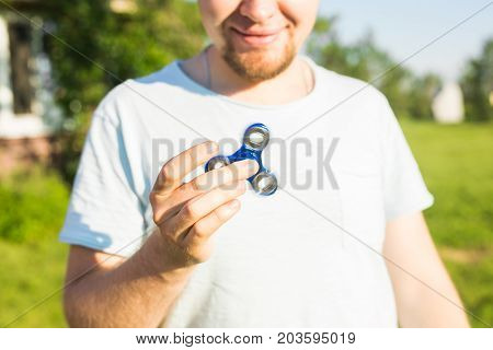 young man playing with a fidget spinner, focus on spinner