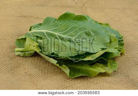 Stack of leaves of raw collard greens on burlap