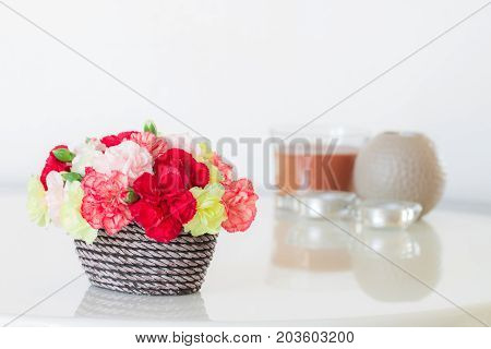 Colorful Carnations In Brown Vase And Candle On Marble Table.
