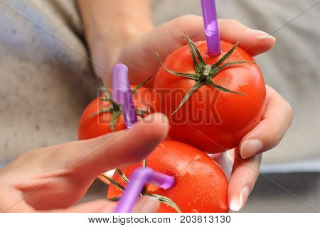 Three Ripe Red Tomatoes with Straws in Woman Hands on Bright Background. Fresh Juice Healthy Food Concept. Tomato as a Vessel with Fresh Juice