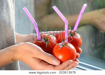 Three Ripe Red Tomatoes with Straws in Woman Hands on Bright Background. Fresh Juice Healthy Food Concept. Tomato as a Vessel with Fresh Juice