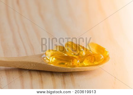 Fish Oil Omega 3 With Vitamin D Capsules Good For Heart Health In Spoon On A Wooden Backguound.