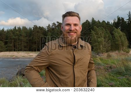 Portrait of a smiling red-haired bearded man in the nature