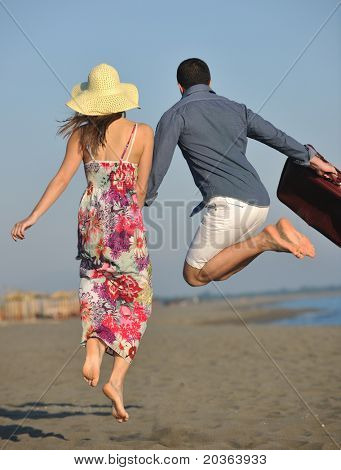 par på strand med Rejsetaske der repræsenterer frihed og funy bryllupsrejse koncept