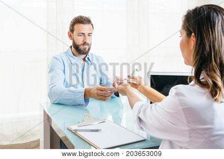Female doctor shows a space chamber and an aerosol inhaler to a patient at her office