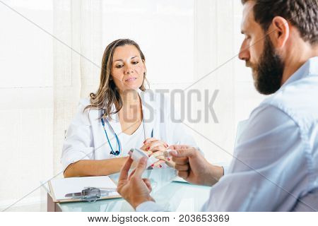 Female doctor supervises a male patient while is using an aerosol inhaler at her office