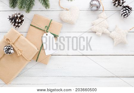 Christmas and New year background. Christmas present gifts box pine cones fir leaves and decorations rustic elements on white wooden background. Creative flat lay top view design