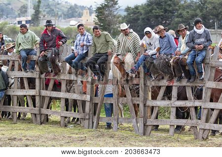 June 10 2017 Toacazo Ecuador: people sitting on the wooden fence watching a rural rodeo performance in the Andes