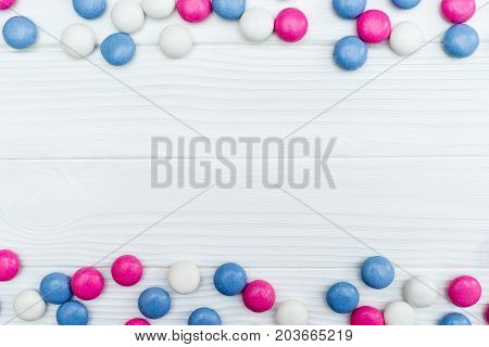 Frame from colorful mint coated candies texture on white wooden background. Top view. Copy space