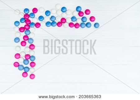 Frame from colorful mint coated candies texture on white wooden background. Top view. Copy space