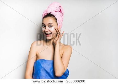 The girl after bathing laughs with a towel on her head, looks after the skin. Isolated on a gray background