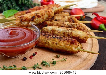 Lula kebab is a traditional Caucasian dish. Chopped meat with skewers. Serve with lavash tomato sauce on a wooden board on a dark background.