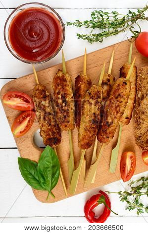 Lula kebab is a traditional Asian dish. Chopped fried meat on skewers. Serve on a board with cereal ciabatta tomatoes. Top view.
