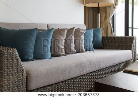 Wicker furniture and colorful pillows. Decoration of living room in colorful theme.